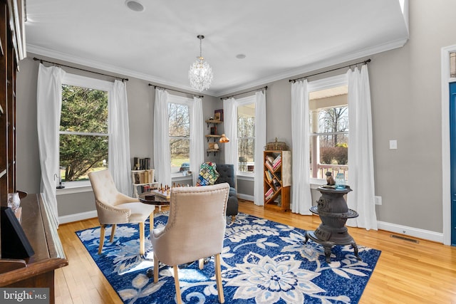 sitting room with visible vents, plenty of natural light, wood finished floors, and ornamental molding