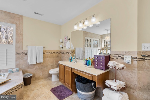 full bathroom with visible vents, toilet, tile walls, tile patterned flooring, and vanity