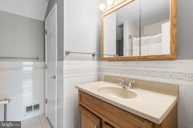 full bath featuring vanity, a wainscoted wall, visible vents, tile patterned flooring, and tile walls
