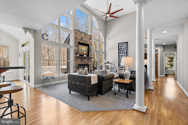 living area with a ceiling fan, wood finished floors, ornate columns, a healthy amount of sunlight, and a fireplace