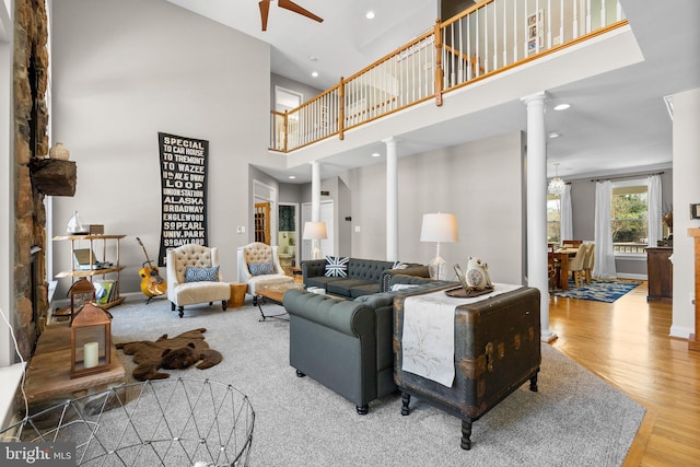 living room with ceiling fan, recessed lighting, a high ceiling, wood finished floors, and ornate columns