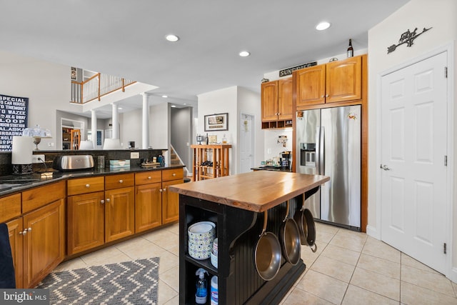 kitchen with light tile patterned flooring, recessed lighting, brown cabinets, and stainless steel refrigerator with ice dispenser
