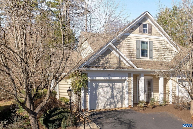 view of front of home with aphalt driveway, covered porch, and an attached garage