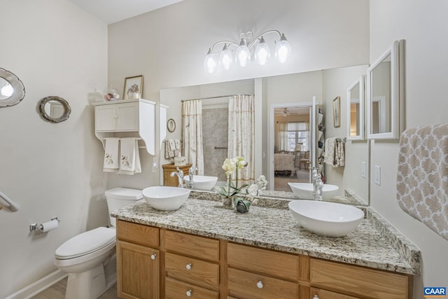 bathroom featuring curtained shower, double vanity, toilet, and a sink