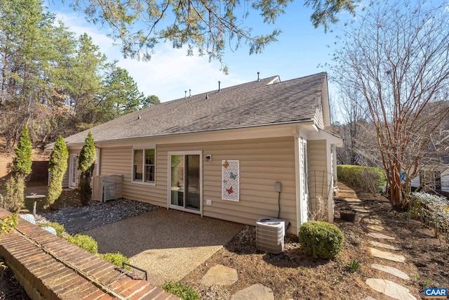 rear view of property featuring cooling unit, a patio, and roof with shingles