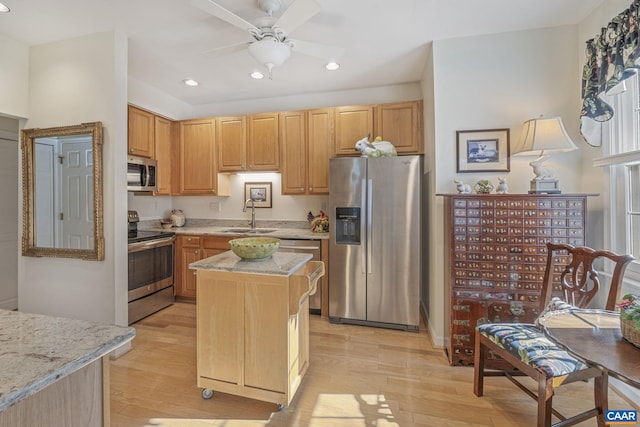 kitchen with a ceiling fan, a sink, light stone counters, stainless steel appliances, and light wood-style floors