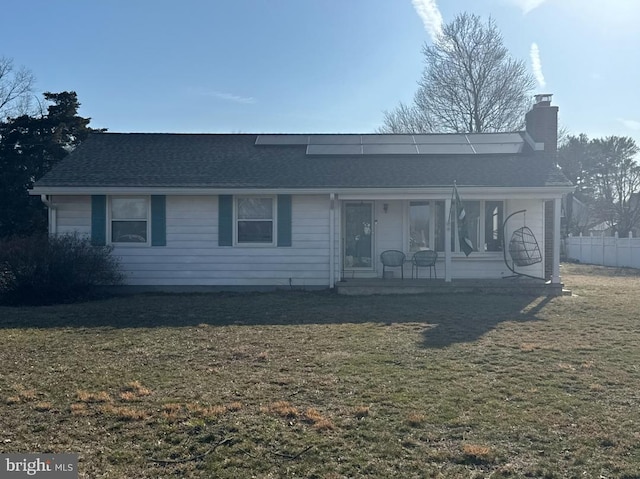 view of front of property featuring a chimney, fence, a front lawn, and a shingled roof