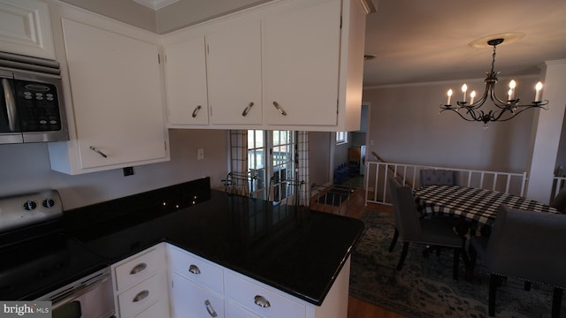kitchen featuring a chandelier, a peninsula, stainless steel appliances, dark countertops, and ornamental molding