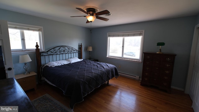 bedroom with wood finished floors, multiple windows, ceiling fan, and baseboard heating