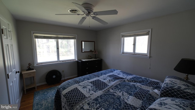 bedroom with a ceiling fan, dark wood-type flooring, multiple windows, and baseboards