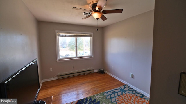 spare room featuring baseboards, baseboard heating, wood finished floors, and ceiling fan