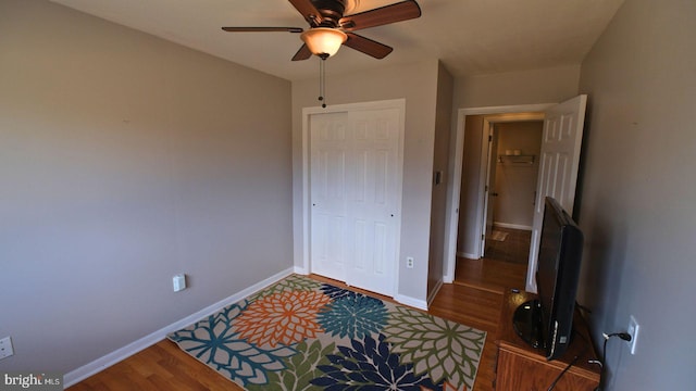 bedroom featuring a closet, baseboards, ceiling fan, and wood finished floors