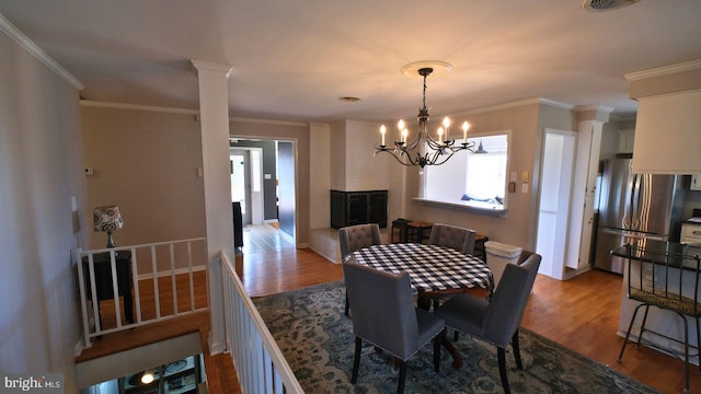 dining space featuring decorative columns, crown molding, and wood finished floors