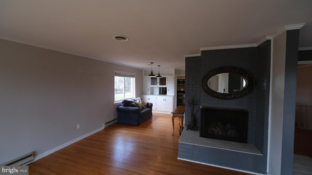 living area featuring baseboard heating, visible vents, wood finished floors, and a fireplace