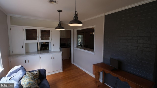 interior space featuring baseboards, visible vents, crown molding, and wood finished floors