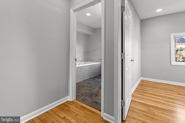 hallway with light wood finished floors, recessed lighting, and baseboards