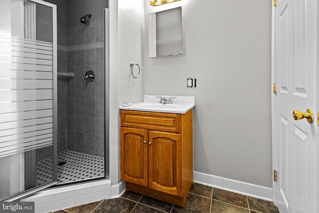 bathroom with vanity, baseboards, a stall shower, and tile patterned flooring