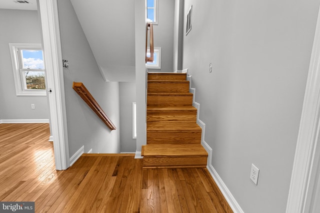 staircase featuring baseboards, wood-type flooring, and visible vents