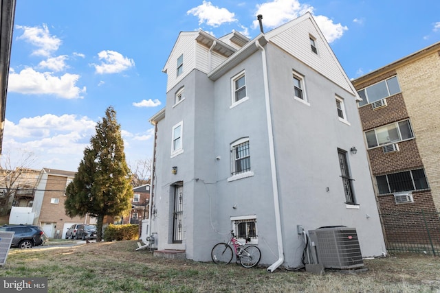 view of side of home featuring cooling unit and stucco siding