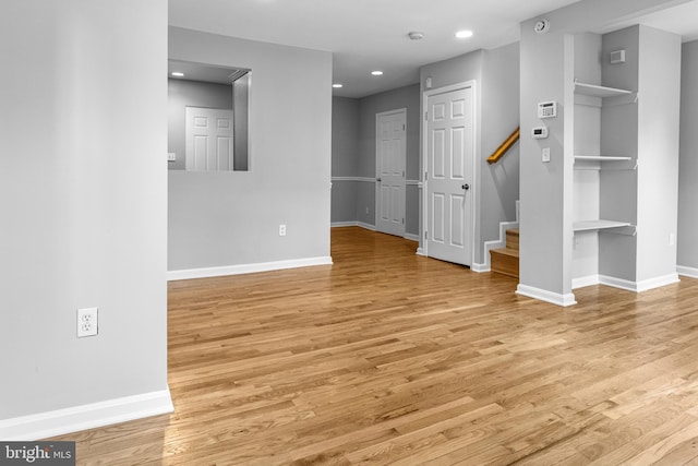 unfurnished room with stairs, recessed lighting, baseboards, and light wood-type flooring