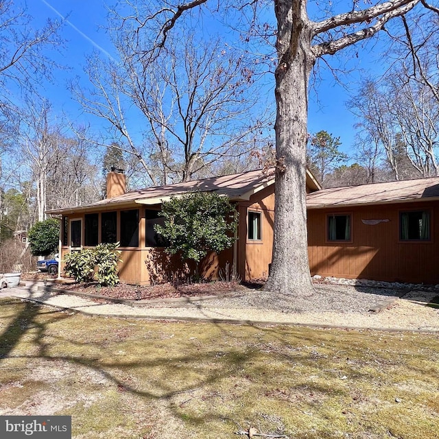 back of property with a sunroom and a chimney