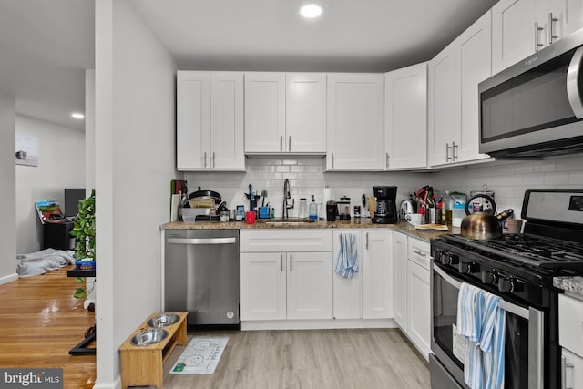 kitchen featuring a sink, light wood-style flooring, white cabinets, and stainless steel appliances