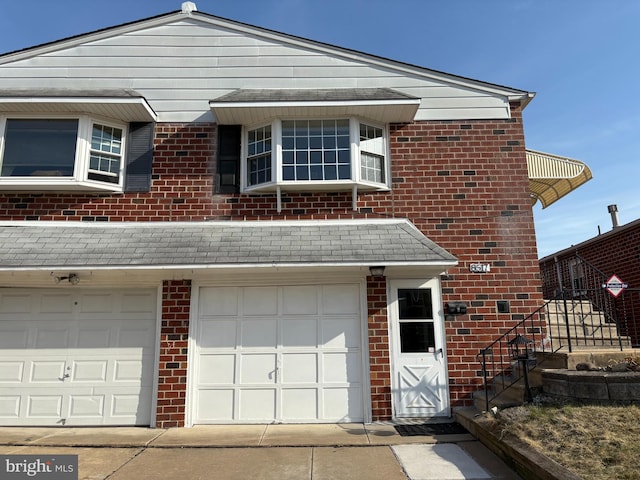 view of front of house with brick siding, a shingled roof, and a garage