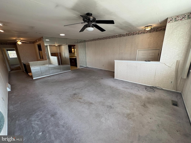 unfurnished living room with visible vents, carpet, and a ceiling fan