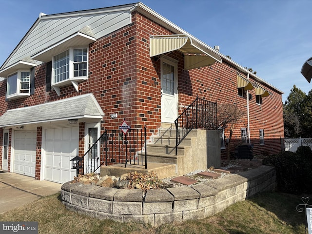 view of side of home featuring brick siding, an attached garage, and concrete driveway