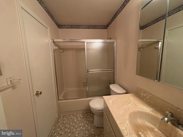 bathroom featuring combined bath / shower with glass door, toilet, vanity, and tile patterned flooring