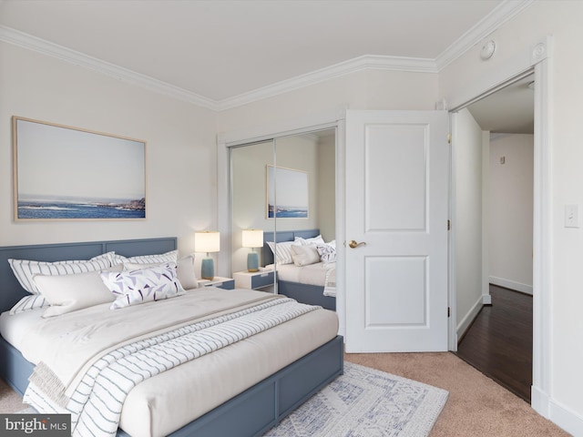 carpeted bedroom with a closet, baseboards, and ornamental molding