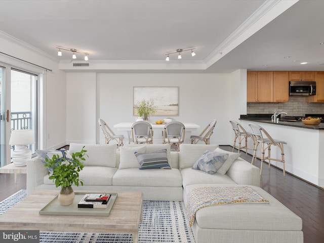 living room with visible vents, wood finished floors, ornamental molding, and track lighting