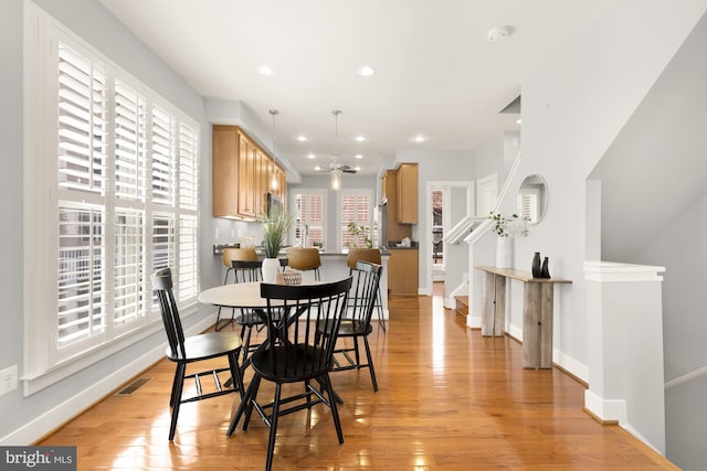 dining room featuring light wood-style flooring, baseboards, and stairway