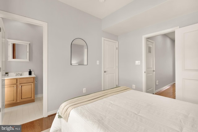 bedroom with baseboards, light wood-style floors, and a sink