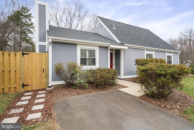 view of front of property with a chimney, fence, roof with shingles, and a gate