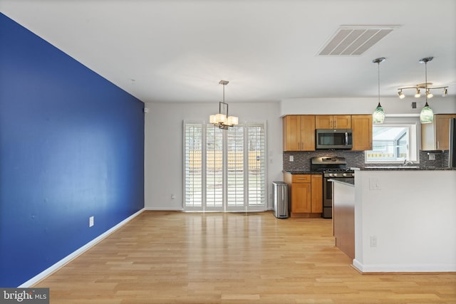 kitchen featuring dark countertops, visible vents, backsplash, light wood-type flooring, and stainless steel appliances