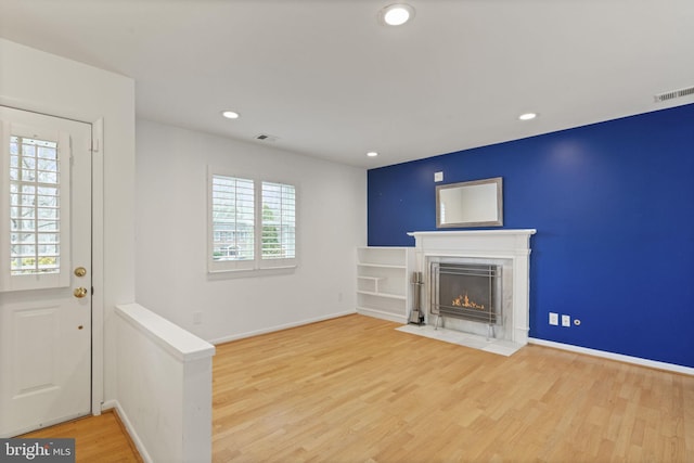 unfurnished living room featuring visible vents, recessed lighting, a fireplace with flush hearth, and wood finished floors