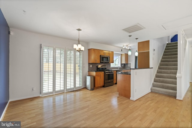 kitchen featuring visible vents, brown cabinets, dark countertops, appliances with stainless steel finishes, and a peninsula