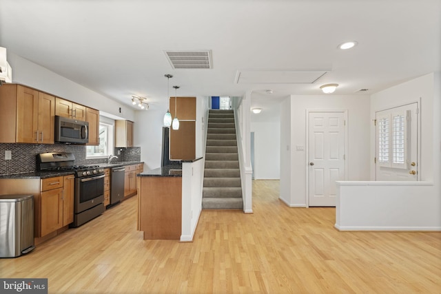 kitchen featuring visible vents, light wood-type flooring, stainless steel appliances, brown cabinets, and backsplash