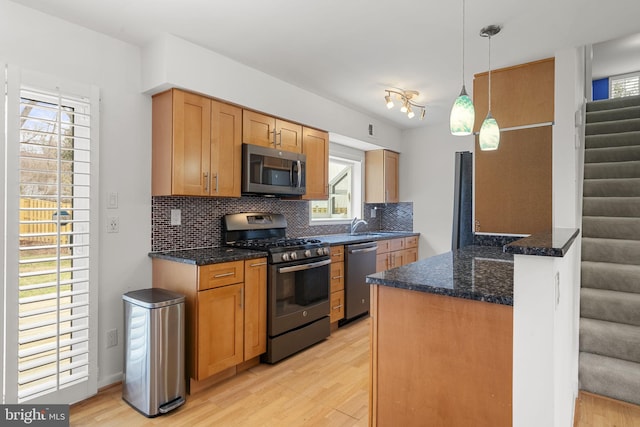 kitchen with light wood finished floors, decorative backsplash, and appliances with stainless steel finishes