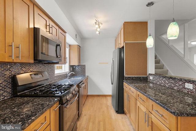 kitchen with a sink, decorative backsplash, light wood finished floors, and stainless steel appliances