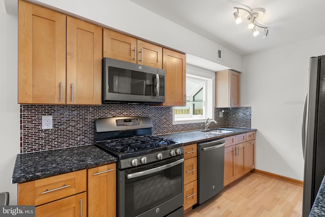 kitchen with visible vents, light wood-type flooring, dark stone counters, appliances with stainless steel finishes, and tasteful backsplash