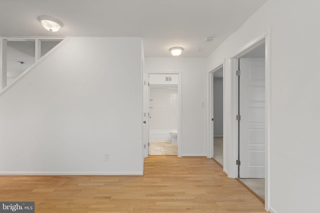 hall featuring light wood-type flooring and baseboards