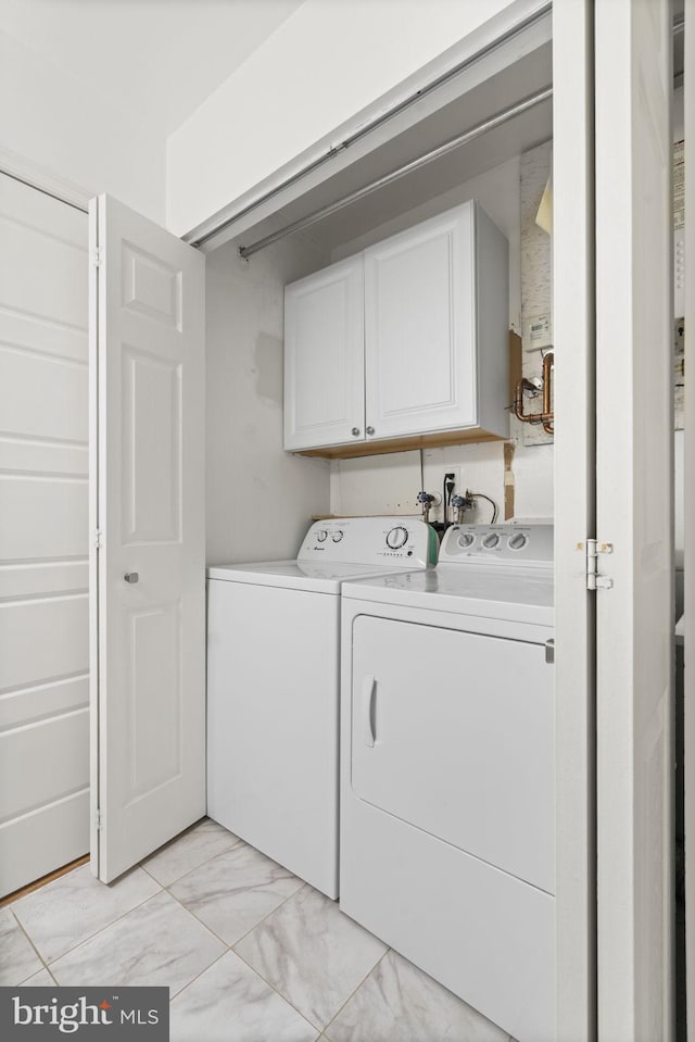 clothes washing area with cabinet space, marble finish floor, and independent washer and dryer