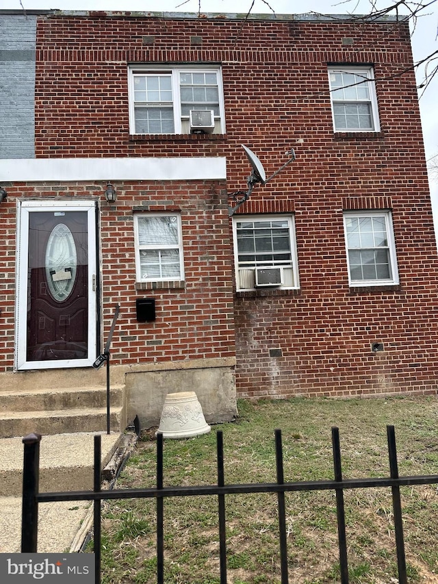 view of front facade with cooling unit, fence, and brick siding