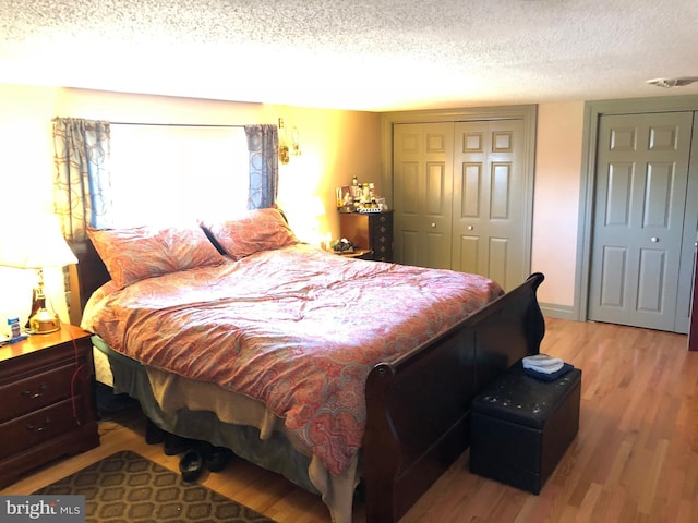 bedroom with a closet, baseboards, a textured ceiling, and wood finished floors