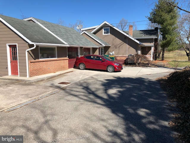 view of property exterior with brick siding and roof with shingles