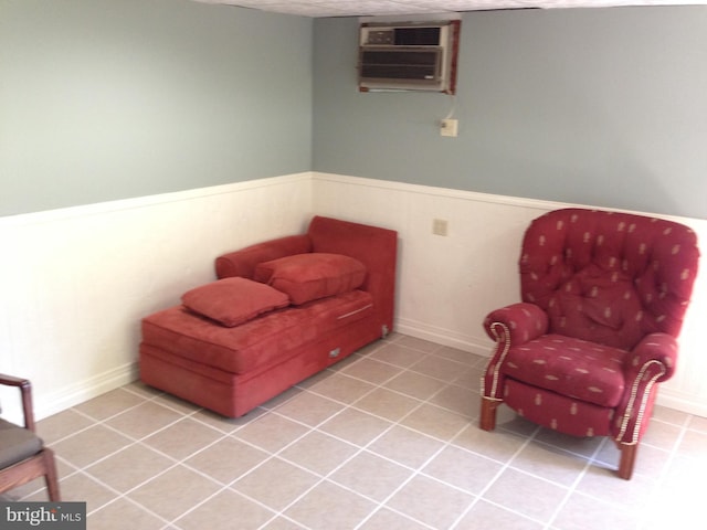 living area featuring tile patterned flooring, a wainscoted wall, and a wall mounted air conditioner