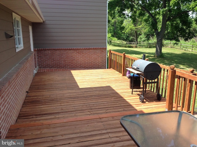 wooden terrace featuring a yard, fence, and a grill