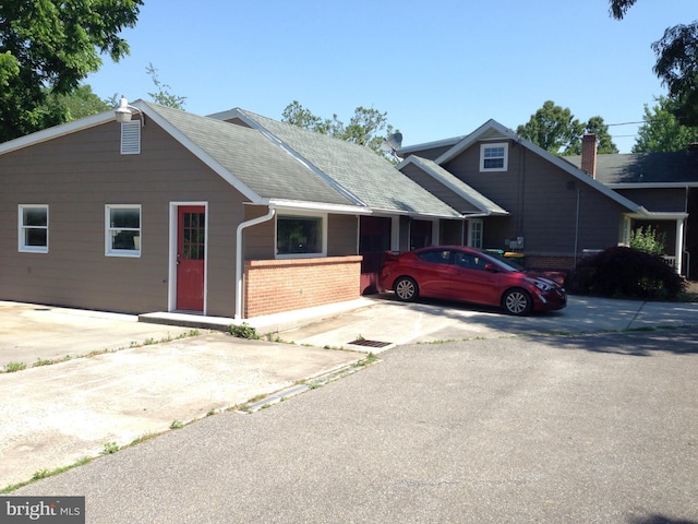 view of front of house with brick siding and roof with shingles